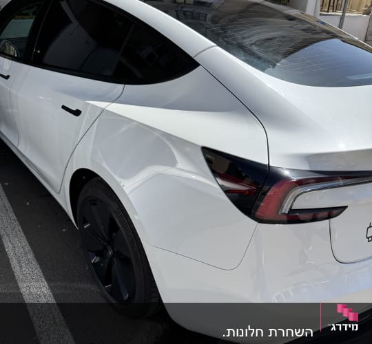 מכונית לבנה עם חלונות כהים וחישוקי גלגלים שחורים